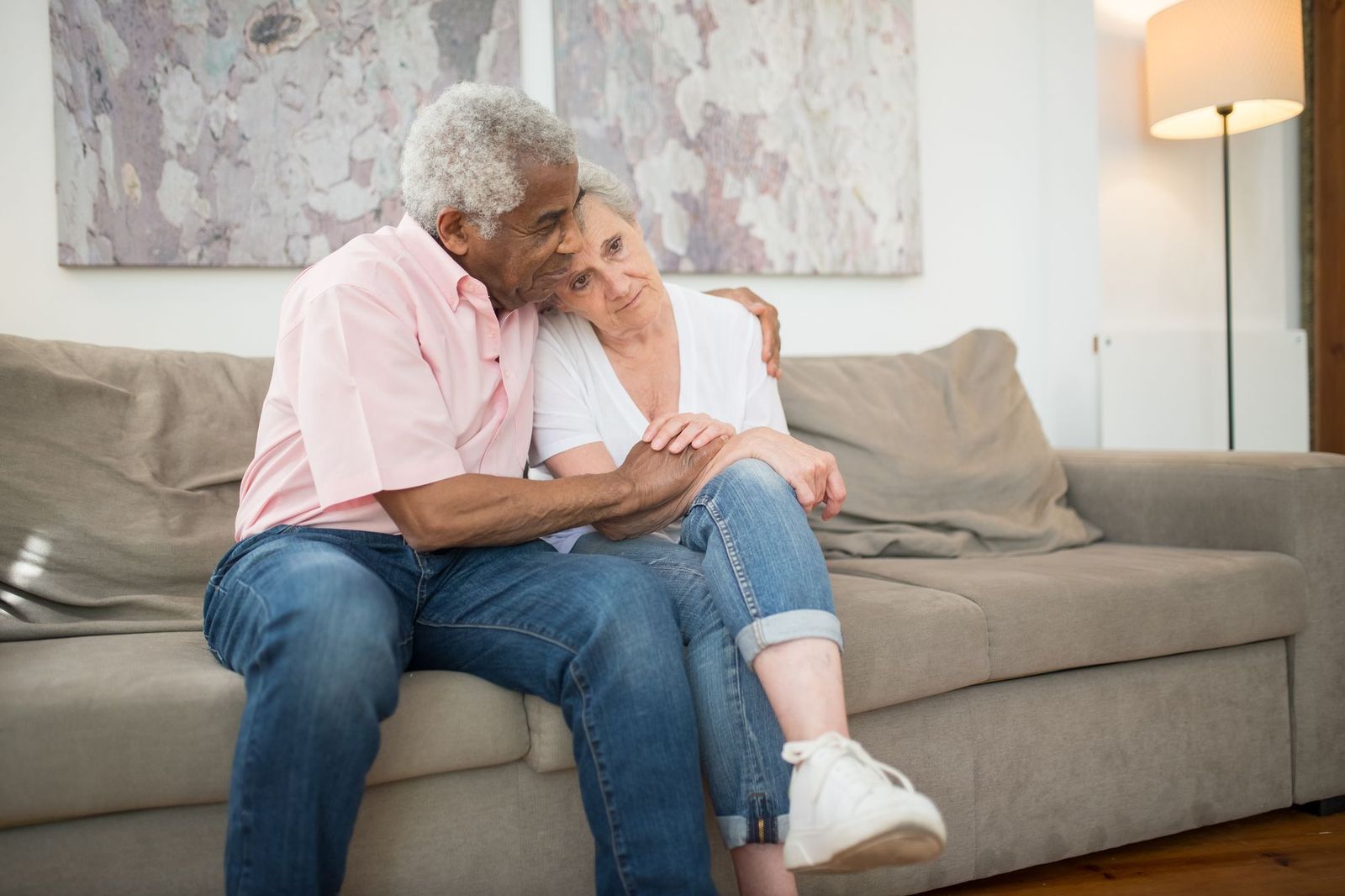 An older couple hug and smile together on the sofa in their living room.